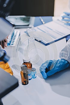 Scientist using microscope in laboratory. Close-up of a researcher's hands adjusting a microscope in a lab setting.