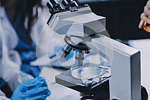 Scientist using microscope in laboratory. Close-up of a researcher's hands adjusting a microscope in a lab setting.