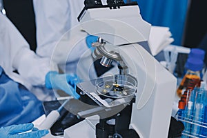 Scientist using microscope in laboratory. Close-up of a researcher's hands adjusting microscope in a lab setting. Scienc