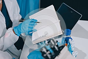 Scientist using microscope in laboratory. Close-up of a researcher& x27;s hands adjusting a microscope in a lab setting.