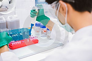 Scientist using pipette transfer sample to Micro Centrifuge Tube for PCR test in Biosafety cabinet