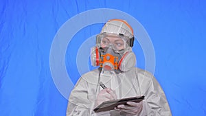 Scientist virologist in respirator makes write in an tablet computer with stylus. Woman wearing protective medical mask