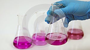 The scientist wear blue nitrile gloves holding Erlenmeyer Conical flask, with purple violet solvent forming reaction boric acid.