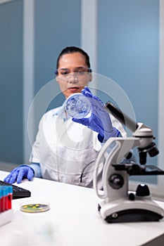 Scientist woman analyzing petri dish with microorganism bacteria