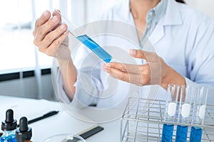 Scientist woman shaking blue liquid in test tube while working to experiment produce vaccine covid-19