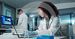 Scientist, woman and typing on laptop with test tube for chemistry, research or experiment at lab. Science, computer and