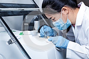 Scientist women using a stainless spatula to scoop substances put to the pedestal instrumentation Fourier Transform Infrared