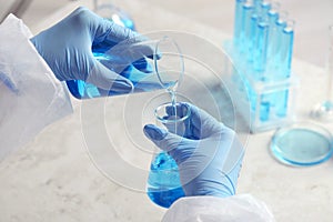 Scientist working with beakers at grey table, closeup