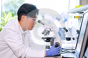 Scientist working in lab. Asian doctor making medical research. Laboratory tools: microscope, test tubes, equipment