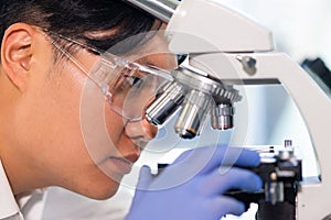 Scientist working in lab. Asian doctor making medical research. Laboratory tools: microscope, test tubes, equipment