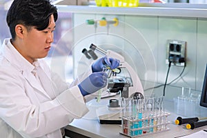 Scientist working in lab. Asian doctor making medical research. Laboratory tools: microscope, test tubes, equipment