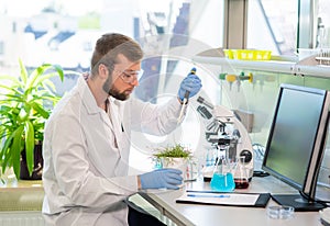 Scientist working in lab. Doctor making microbiology research. Laboratory tools: microscope, test tubes, equipment