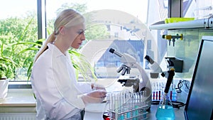 Scientist working in lab. Female doctor making medical research. Laboratory tools: microscope, test tubes, equipment
