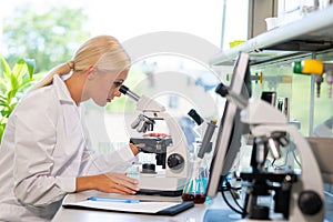 Scientist working in lab. Female doctor making medical research. Laboratory tools: microscope, test tubes, equipment