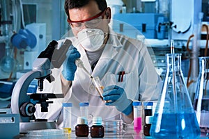 Scientist working in microscope with chemical material samples in biotechnology lab