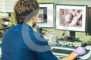 Scientist works at a electron microscope control pannel with two