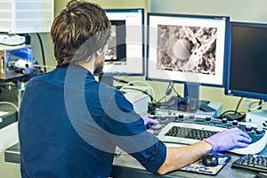 Scientist works at a electron microscope control pannel with two