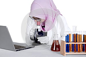 Scientist works with microscope and laptop