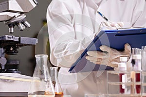 Scientist is writing data after analysis and research chemical test in a laboratory