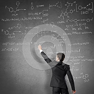 Scientist writing formulas on chalkboard