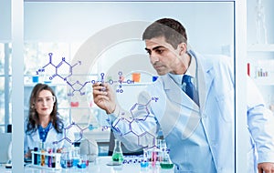 Scientists drawing chemical formulas on clear board in science laboratories