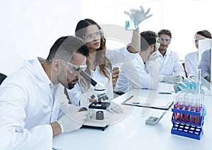 Scientists examining attentively pipette with blue fluid in laboratory