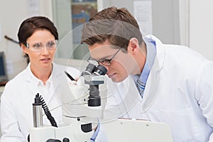 Scientists looking attentively in microscope