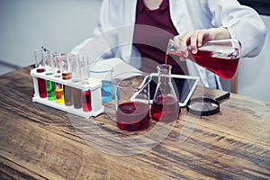 Scientists looking solution result to tablet screen on lab table with laboratory accessories