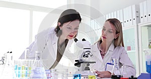 Scientists with microscope perform tests or research in clinical laboratory.