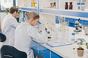 Scientists with microscopes in laboratory