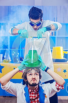 Scientists pouring liquids to big flask