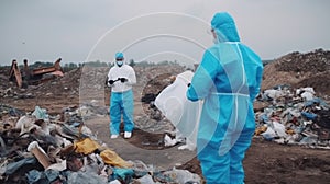 Scientists with rotective suit, investigated and inspected garbage pile in landfill