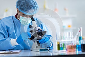 Scientists wear protective clothing looking for microscopes while doing medical research in a science laboratory