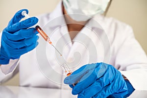 Scientists wearing masks and gloves Holding a syringe with a vaccine to prevent covid-19