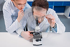 scientists in white coats and eyeglasses working with reagent together