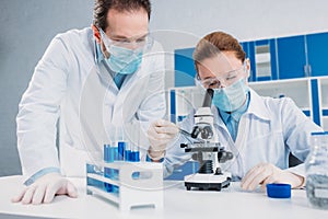 scientists in white coats, medical gloves and goggles making scientific research together photo