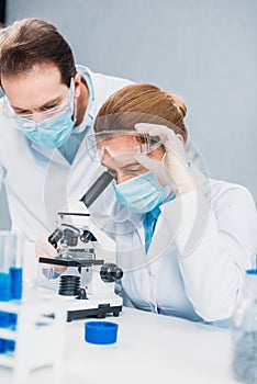 scientists in white coats medical gloves and goggles making scientific research together