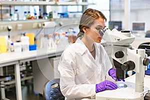 Scientists woman looking through microscope in lab