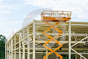 Scissor lift on the background of the metal frame of the newly built factory