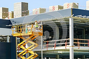 Scissor lift on the background of the metal frame of the newly built factory