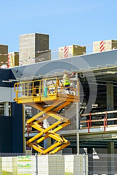 Scissor lift on the background of the metal frame of the newly built factory