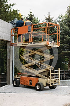 Scissor Lift Platform with workers on a construction site near the wall