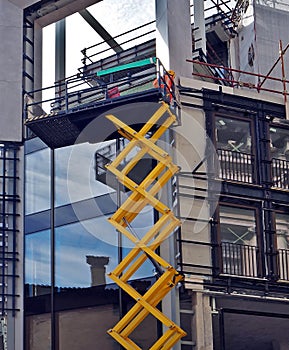 Scissor lift, at work on a building facade under construction