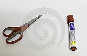 A scissor and a marker pen in white background