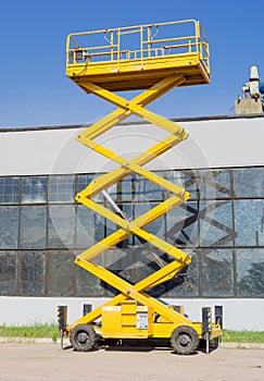 Scissor self propelled lift on the background of industrial building