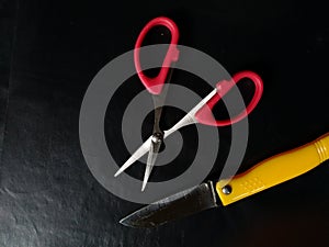 Scissor and a small knif in a black background