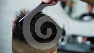 Scissoring a man's hairstyle in a barbershop, close-up.