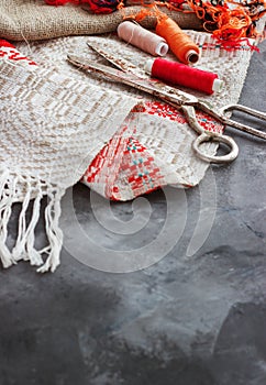 Scissors, bobbins with thread and needles, striped fabric. Old sewing tools on the background. Vintage Background