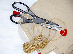 Scissors, coarse thread lie on Kraft paper on a light wooden background