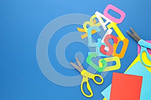 Scissors and colored paper for children`s art on blue background